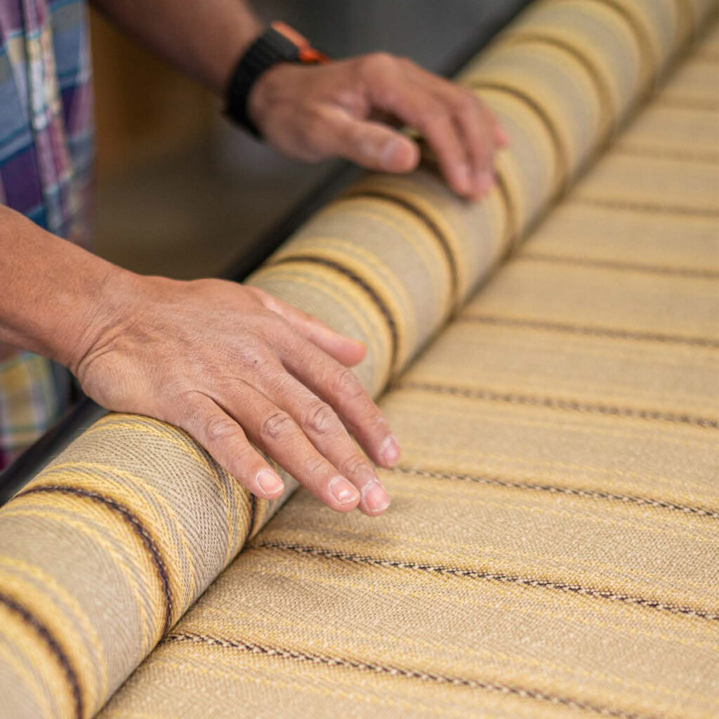 unrolling a roll of striped woven fabric