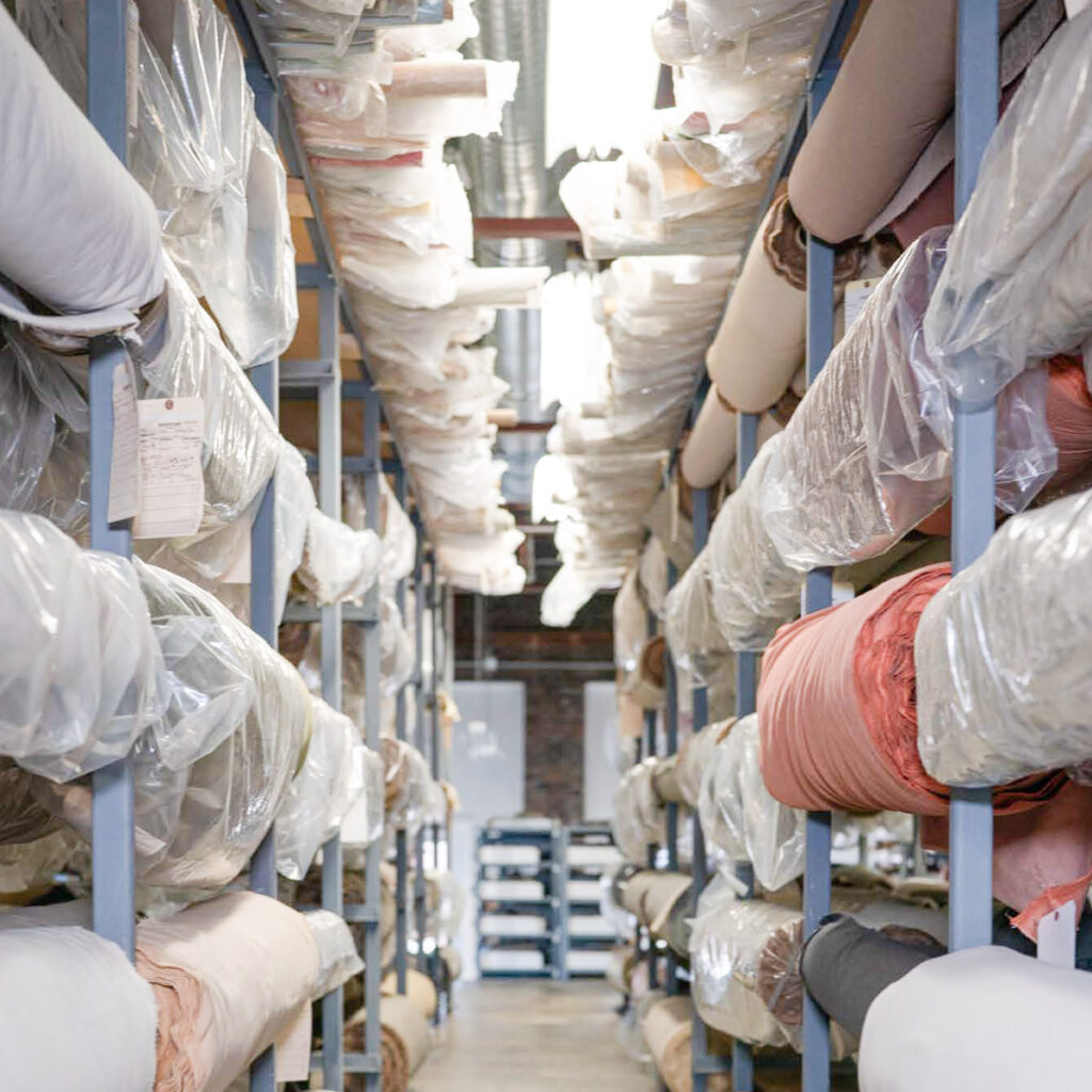 interior of a large warehouse space with fabric rolls on racks, wrapped in plastic